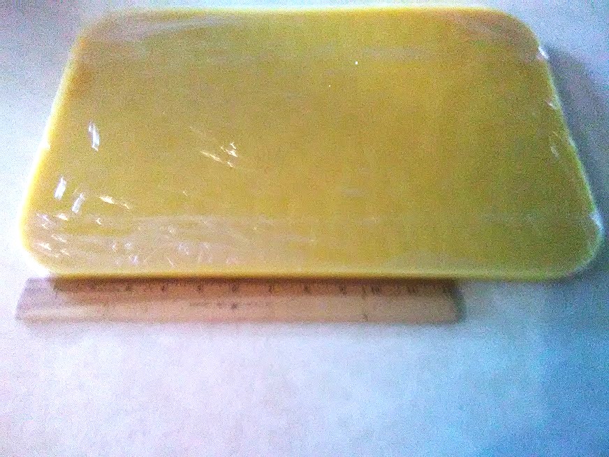 A ¾ inch thick layer of beeswax wrapped in cellophane after cooling and removal from the turkey roaster next to a twelve inch ruler. Photo credit: Richard Wahl